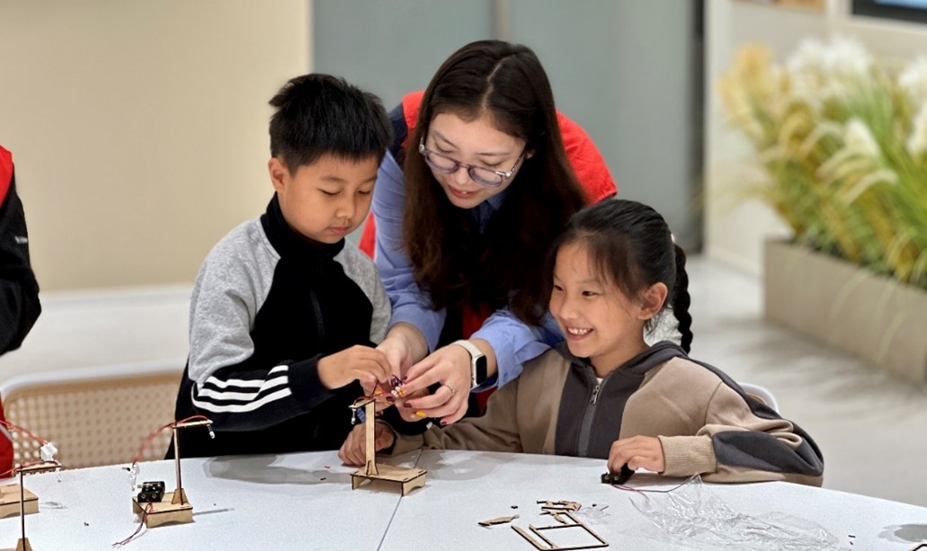 1729488631769815.jpg 图3 志愿者帮助小朋友制作路灯.jpg